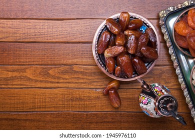 Plate with dates, coffee pot  on brown wooden table. Ramadan background.  Top view.
