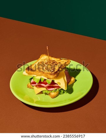 Plate with delicious club sandwich with ham, lettuce, cheese, tomato and avocado over red green background. Concept of fast food, taste, cooking, ingredients. Complementary colors. Poster, ad