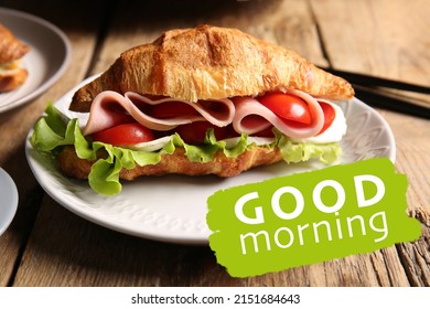 Plate with delicious croissant sandwich and text GOOD MORNING on wooden background, closeup