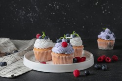 Plate Of Delicious Cupcakes With Blueberries, Raspberries And Mint On Black Background