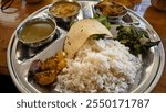 A plate of delicious Dal Bhat with chicken curry, cracker, curry sauce, and some vegetables