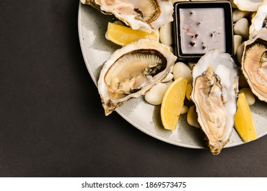 Plate of delicious fresh steamer clams with sauce in the middle. Over black background. Sea food concept, healthy meal.