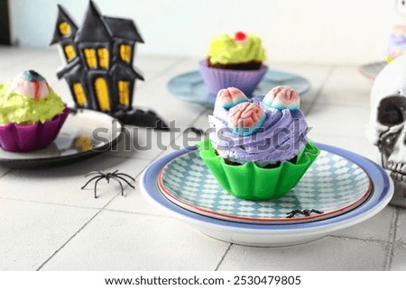 Plate with delicious Halloween cupcake and candies on light background, closeup