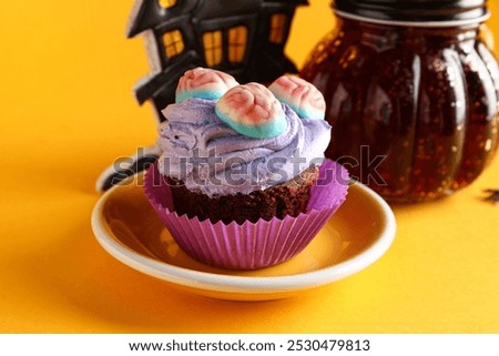 Plate with delicious Halloween cupcake and candies on orange background, closeup
