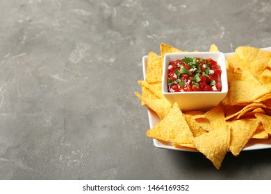 Plate With Delicious Mexican Nachos Chips And Salsa Sauce On Grey Table. Space For Text