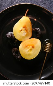 Plate with delicious poached pear and honey dipper stick, closeup