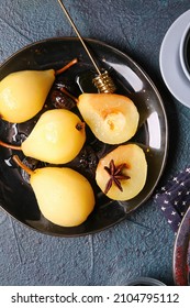 Plate with delicious poached pears and prunes on dark background