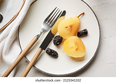 Plate with delicious sliced poached pear, prunes and cutlery on light table