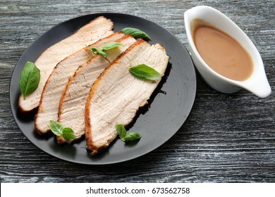 Plate With Delicious Sliced Turkey And Gravy Boat On Wooden Table