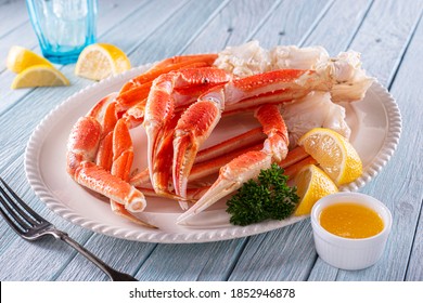 A Plate Of Delicious Snow Crab Leg Clusters With Lemon, Parsley And Melted Butter.