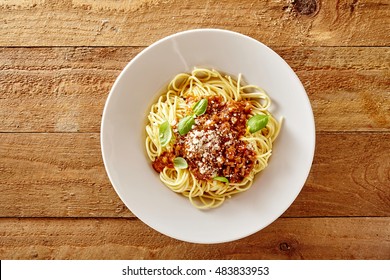 Plate of delicious spaghetti Bolognaise or Bolognese with savory minced beef and tomato sauce garnished with parmesan cheese and basil, overhead view