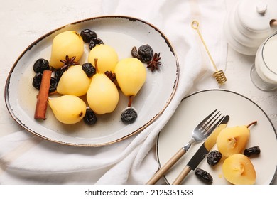 Plate and dish with delicious poached pears and prunes on light background