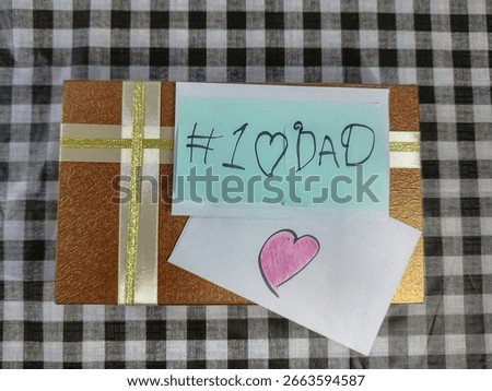 A plate of donuts with a gift box and “#1 DAD” note arranged on black and white cloth, perfect for a Father's Day tribute