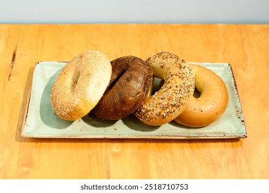 A plate with five assorted bagels, showcasing different flavors and toppings on a wooden table. - Powered by Shutterstock