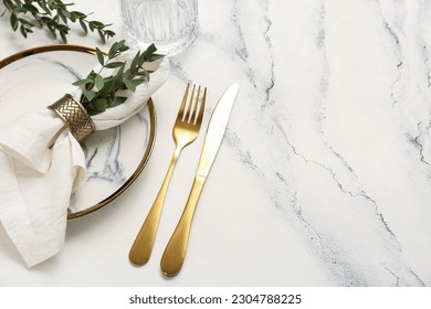 Plate with folded napkin and gold cutlery on grunge white background