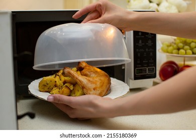 A plate of food in the microwave covered with a lid. The benefits and harms of microwave radiation for food. Plastic lid for the microwave oven. Bright and beautiful kitchen with a microwave and food. - Shutterstock ID 2155180369