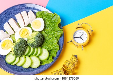 A Plate With Food On Pink And Blue Background, Interval Fasting Concept