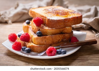 plate of french toasts with fresh berries on a wooden table - Shutterstock ID 2035566074