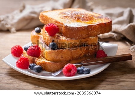 plate of french toasts with fresh berries on a wooden table