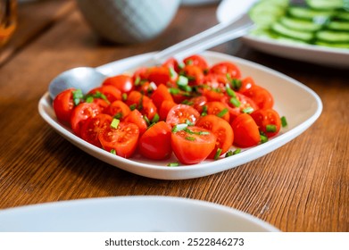 A plate of fresh cherry tomatoes sprinkled with chives on a wooden table, beautifully arranged as part of a vibrant breakfast setting - Powered by Shutterstock