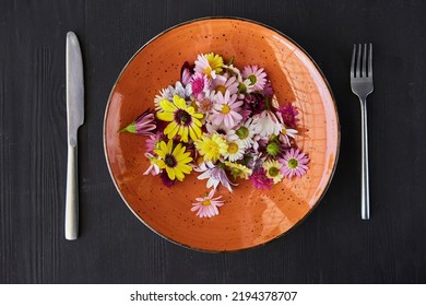 A Plate With Fresh Flowers And Cutlery With A Fork And Knife. The Concept Of Plant-based Nutrition, Vegetarianism And Organic Food. Humor About The Lack Of Normal Food.