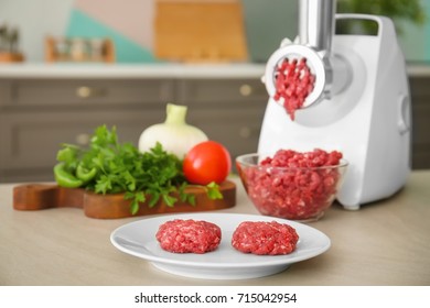 Plate with fresh forcemeat and meat grinder on kitchen table