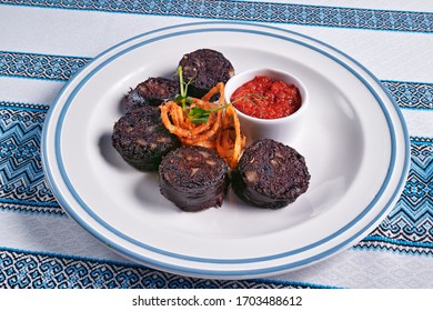 Plate with fried blood sausage, served with fried onions and spicy sauce.