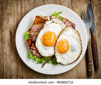 plate of fried eggs and bacon on white plate, top view