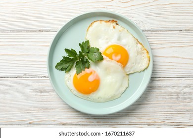 Plate with fried eggs on wooden background, top view