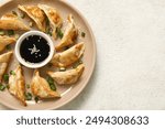 Plate with fried Japanese gyoza and bowl of soy sauce on white background