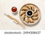 Plate with fried Japanese gyoza and bowl of soy sauce on white background