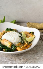 A Plate Of Fried Pollock With Spinach And Rice On The Table