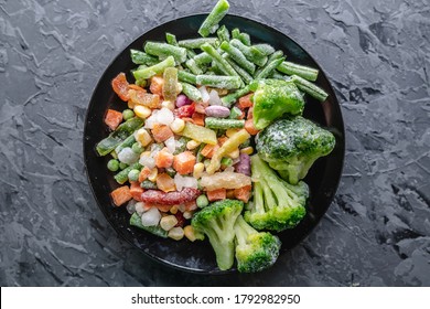 Plate of frozen vegetables on a gray table. Concept of saving time on cooking dinner and convenient storage of ready made frozen dishes.