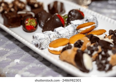 Plate full of an assortment of desserts such as cookies, chocolate covered strawberries, mini cannoli and more. - Powered by Shutterstock