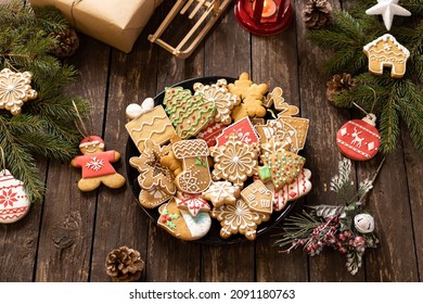 Plate full with cookies in winter holiday themes, gingerbread Santa Claus man, snow flake, Christmas sock, Christmas tree, snowy house, symbolizing cold weather and warm home concept - Powered by Shutterstock