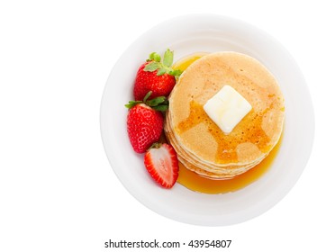 Plate Full Of Fluffy Golden Pancakes With Strawberries And Maple Syrup In Overhead View