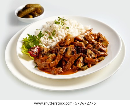 Plate of Goulash Stroganoff isolate on white background with basmati rice and cucumbers