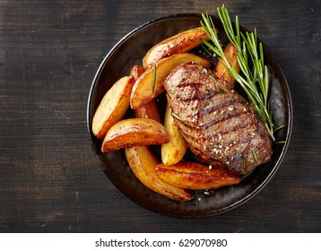 Plate Of Grilled Beef Steak And Potatoes On Dark Table, Top View