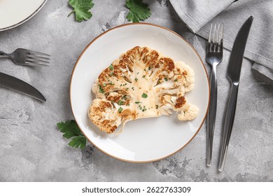 Placa con filete de coliflor a la parrilla y perejil sobre fondo gris