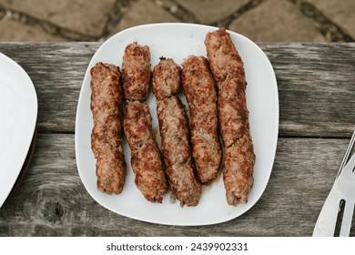 plate of grilled kebab on wooden background.  Top view. Barbecue sausages presented on the fire. Appetizing food on the fire. Weekend vacation in nature. Copy past