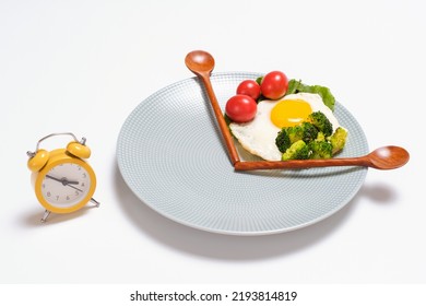 Plate With Healthy Food, Wooden Spoons And Alarm Clock On White Background Top View, Intermittent Fasting Concept.