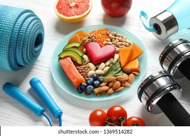 Plate With Heart-healthy Products And Sports Equipment On Wooden Background