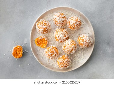 plate with homemade vegan energy balls with dried apricots and coconut. healthy raw vegetarian dessert. Gray background. top view
