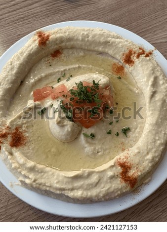 Plate of hummus with tomato, parsley, olive oil, and paprika.