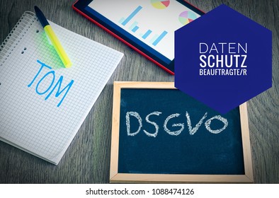 Plate with the inscription DSGVO (Datenschutzgrundverordnung) and TOM in English GDPR (General Data Protection Regulation) with a tablet and block for the introduction of the DSGVO in the EU