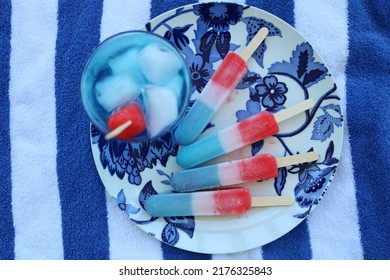 Plate Of Juicy Frozen Popsicles With Bomb Pop Drink On Beach Towel