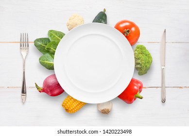 Plate, knife, fork and vegetables on white wooden table. Top view. - Powered by Shutterstock