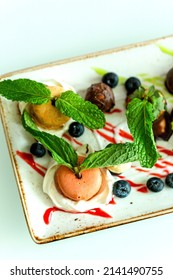 Plate Of Macarons And Truffles Dessert Garnished With Fresh Peppermint Leaves