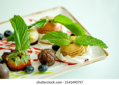 Plate Of Macarons And Truffles Dessert Garnished With Fresh Peppermint Leaves