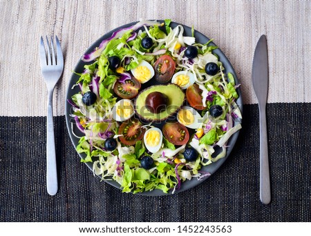 Plate on a burlap cloth background with keto food:quail eggs,cherry tomatoes,
avocado,olive oil,berries,spinach.
Ketogenic low carbs diet concept,top 
view.Healthy fats,clean eating for weight loss.